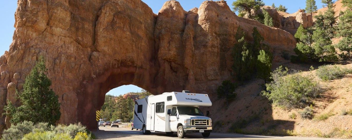 RV driving through a tunnel in a rock outcropping.