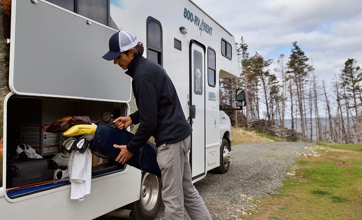 man storing golf clubs in rv