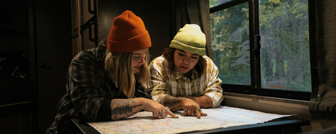 Two young women sitting at RV table pointing to a map.